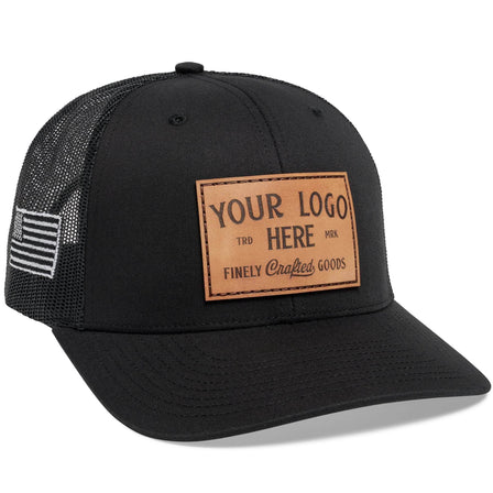 The C12-CTM Black Mesh Trucker Hat by BLVNK features bold white Custom cursive with YOUR LOGO HERE text on the front panel, offering a stylish way to showcase branded hats that reflect your style or logo.