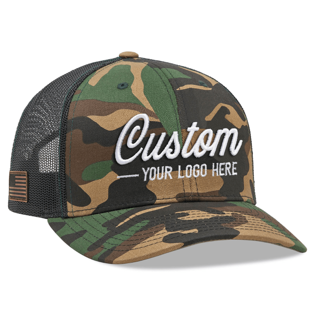 The Richardson 112P Printed Trucker Hat by Richardson is a camouflage cap with a black mesh back, featuring white embroidered text Custom Your Logo Here and an American flag patch on the brims side, perfect for branded or company logo hats.