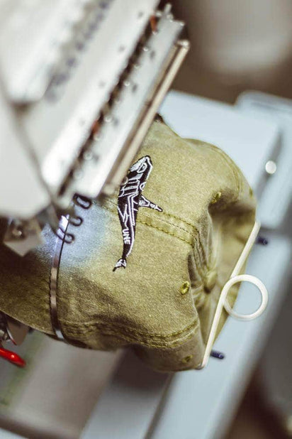 Close-up of eco-friendly custom hat embroidery using recycled Madeira Polyneon thread on a machine at Dekni Creations, USA-made