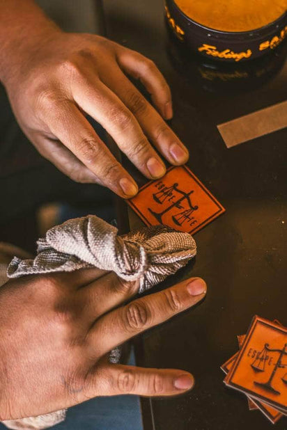Handcrafted full grain vegetable-tanned leather patch being engraved for custom hats at Dekni Creations