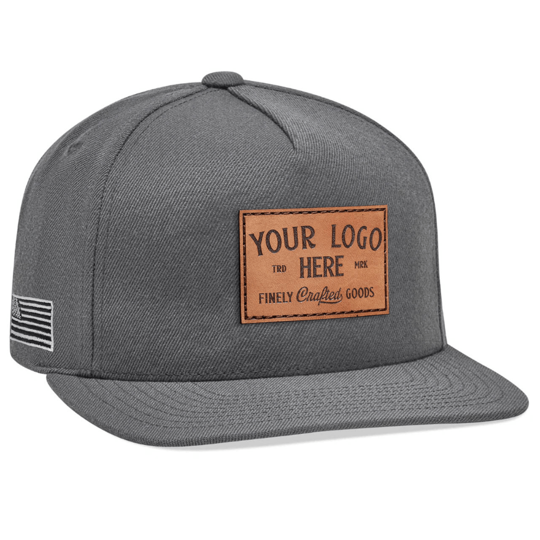 The Yupoong 5089M High-Profile 5-Panel Flat Bill Snapback Hat is gray with white embroidered Custom - Your Logo Here text on the front, perfect for company logos. It features a flat brim and a side patch with a flag design.